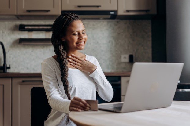 Mujer mirando un portatil con mano en el corazón